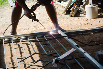 Workers weld iron with stick welding