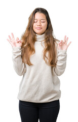 Young beautiful brunette woman wearing turtleneck sweater over isolated background relax and smiling with eyes closed doing meditation gesture with fingers. Yoga concept.