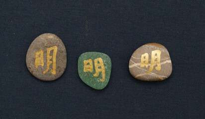 Chinese character ming or Japanese mei, meaning bright, written on a rock pebble