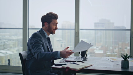 Smiling boss talking video meeting at company office closeup. Man holding papers