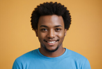 A young man wearing a blue shirt smiles confidently against a mustard yellow background, exuding a relaxed and approachable demeanor in this vibrant portrait setup.