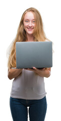 Naklejka premium Blonde teenager woman using computer laptop with a happy face standing and smiling with a confident smile showing teeth