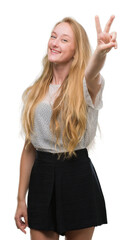 Blonde teenager woman wearing moles shirt smiling looking to the camera showing fingers doing victory sign. Number two.