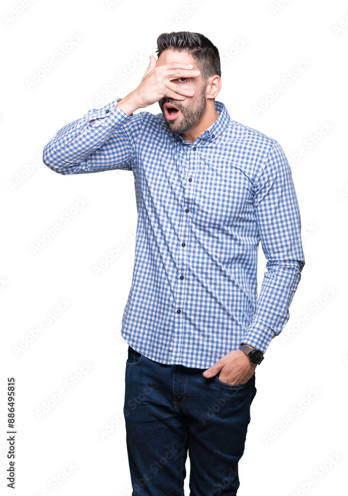 Wall mural young handsome man over isolated background peeking in shock covering face and eyes with hand, looki