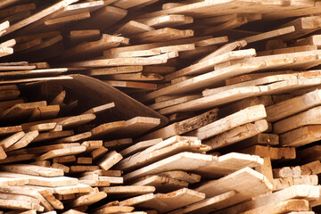 Stack of rough wooden planks creating a pattern of lines and textures with a rustic appearance suitable for woodworking and construction themes