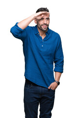 Fototapeta premium Young handsome man over isolated background very happy and smiling looking far away with hand over head. Searching concept.
