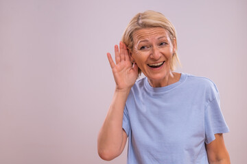Portrait of mature woman listening on the gray background.