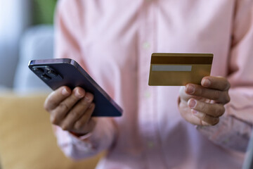 Close-up of person holding smartphone and credit card demonstrating online shopping or mobile payment. Technology, finance, and ecommerce concepts depicted in modern lifestyle