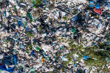 Aerial top view of large urban landfill filled with various types of waste and scattered greenery, environmental pollution. 