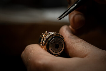 Jeweler puts diamond to golden wedding luxury ring. - Powered by Adobe