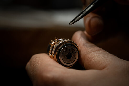 Jeweler puts diamond to golden wedding luxury ring.