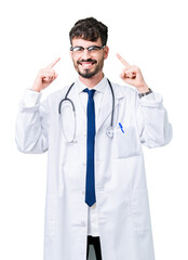 Young doctor man wearing hospital coat over isolated background Smiling pointing to head with both hands finger, great idea or thought, good memory