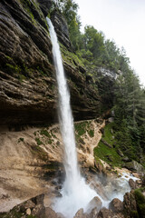 Fototapeta premium Perichnik waterfall is a beautiful drop from the mountain cliff, in Triglav National Park. Slovenian waterfall. Long for walking and trekking, enter inside the cave to admire it. Power and majesty.