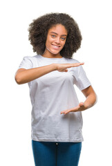 Young afro american woman over isolated background gesturing with hands showing big and large size sign, measure symbol. Smiling looking at the camera. Measuring concept.