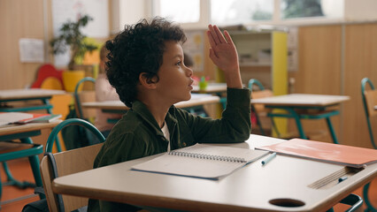 African American school boy son child guy little kid schoolboy pupil student study learn elementary education studying learning class lesson study rise hand up ask tutor answer teacher question talk