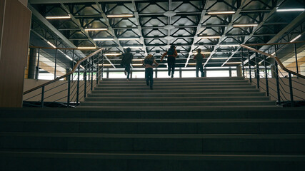 Back view fast unrecognizable schoolboys schoolgirls together running children run on stairs little classmates pupils Caucasian African kids boys girls rush hurry school corridor dark hall upstairs