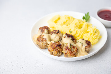 Swedish noisettes (fricandel) with mashed potatoes, Brune Sos creamy sauce and lingonberry (cranberry) sauce. Traditional meatballs with garnish. Copy space. Selective focus, close-up.