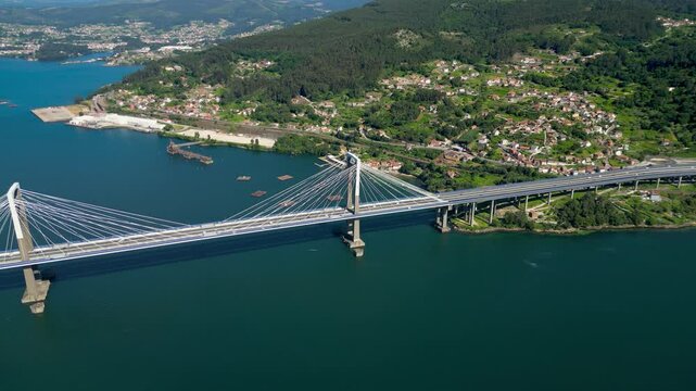 Aerial drone point of view of Vigo. View of Rande Bridge and Vigo Ria. Mussels farming structures aligned in the middle of the water. Beautiful Galician green landscape. Drone forward, camera tilt up