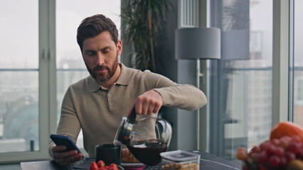 Busy businessman pouring coffee cup at panoramic kitchen closeup. Man reading