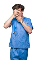 Young doctor wearing medical uniform over isolated background Covering eyes and mouth with hands, surprised and shocked. Hiding emotion