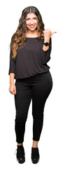 Obraz premium Beautiful young woman with long hair smiling with happy face looking and pointing to the side with thumb up.