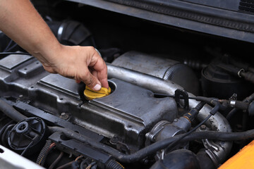 Close-up of a diesel engine oil filler cap. The man's hand checks whether the oil filler cap is tightened tightly. Car repair or maintenance concept. The mechanic inspects the car