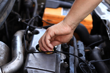 Obraz premium Close-up of a diesel engine oil filler cap. The man's hand checks whether the oil filler cap is tightened tightly. Car repair or maintenance concept. The mechanic inspects the car