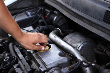 Close-up of a diesel engine oil filler cap. The man's hand checks whether the oil filler cap is tightened tightly. Car repair or maintenance concept. The mechanic inspects the car