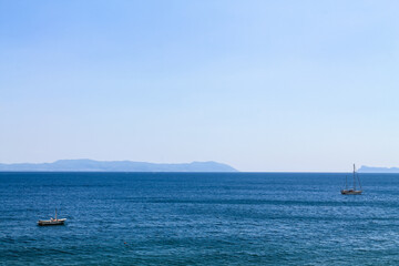 Fototapeta premium Two sailboats on the sea on the mountains background in Italy, the Bay of Naples