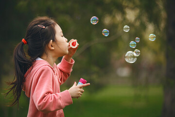 Child Girl Launching Soap Bubbles By Blow it in Green Park on Sunny Day
