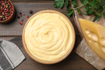 Tasty cheese sauce, pepper and parsley on wooden table, flat lay