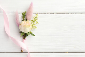 Small stylish boutonniere and ribbon on white wooden table, top view. Space for text © New Africa
