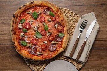 Delicious pizza with vegetables, salami, mushrooms and basil served on wooden table, flat lay