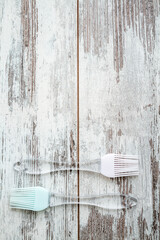 Two silicone basting brushes with transparent handles, one with a pink head and the other with a...