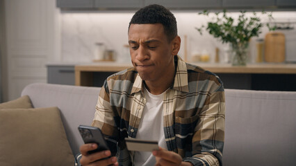African American man buyer user biracial guy ethnic male client customer order online delivery banking payment booking shopping with credit bank card and mobile phone failure thinking pensive problem