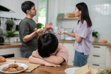 Young little Asian kid feel sad upset, boring while parent fighting arguing or quarrel, sad little boy frustrated with psychological problem caused by mom and dad family conflicts or violence concept.