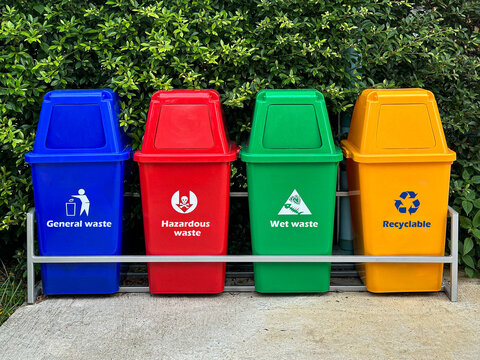 The different typy of garbage bins separation according to the color and symbol and wording of the bin with green tree at back, The concept is waste classification