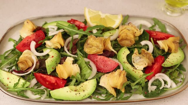 Warm salad with rapans (snails), tomatoes, avocado, arugula, black olives, onions and olive oil. Traditional seafood salad. Close-up, selective focus, remove.