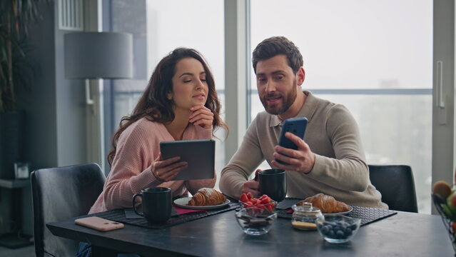 Happy sweethearts discussing smartphone screen at weekend breakfast closeup - Powered by Adobe