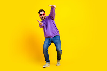 Full size photo of handsome young guy have fun dancing sunglass wear trendy violet outfit isolated on yellow color background