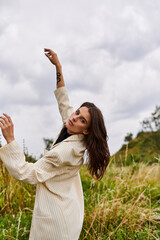 A beautiful young woman in white attire stands in a field, enjoying the summer breeze.