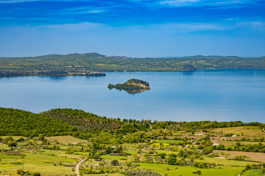 The enchanting panorama of Lake Bolsena, seen from the panoramic terrace of the ancient medieval village of Montefiascone, Viterbo, Italy. Mist on the horizon on a summer evening.
