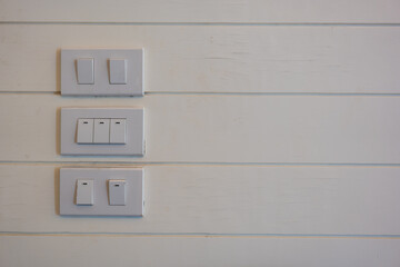 A panel of a white switch on off lights located on old wood white wall