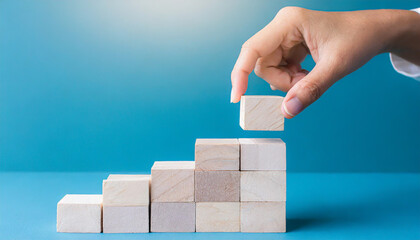 Business concept growth success process, Close up man hand arranging wood block stacking as step stair on paper blue background, copy space.