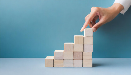 Business concept growth success process, Close up man hand arranging wood block stacking as step stair on paper blue background, copy space.