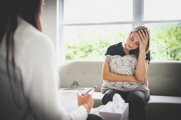 Psychotherapist supporting depressed teenage girl on couch during appointment in office a Psychotherapy concept
