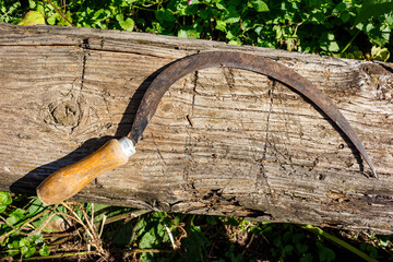 Garden tool sickle lying on a log