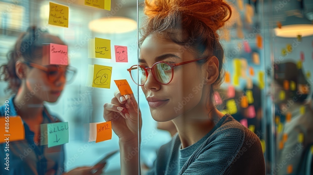 Poster dynamic group of young professionals brainstorming with sticky notes on a glass wall in a modern off