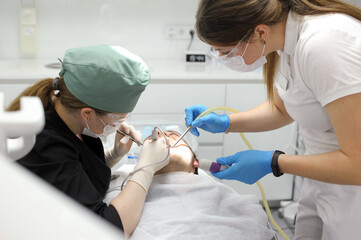 Attractive young woman in stomatology clinic with male dentist. Healthy teeth concept.