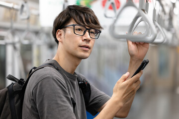 電車でスマホを見る男性
